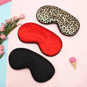 Close-up of three faux silk sleep masks in leopard, red, and black on pink background
