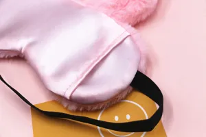 Detail of pink plush rabbit eye mask showing soft satin lining and elastic strap