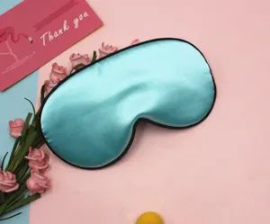 Close-up of a premium light blue satin sleep mask with elegant black piping and smooth texture