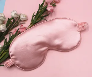 Detailed view of a soft pink silk-like sleep eye mask surrounded by decorative roses