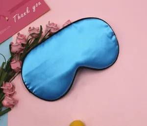 Detailed close-up view of the smooth blue satin sleep mask featuring premium black piping