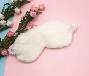 Close-up of white plush rabbit fur eye mask with soft satin elastic strap for sleeping.