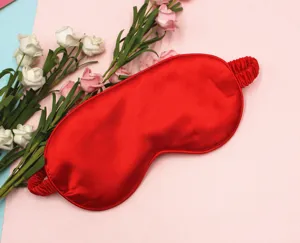 Detailed view of smooth red silk eye mask for sleep on a decorative floral background