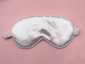 Soft silver silk sleep mask for blackout and comfort shown on a soft pink backdrop