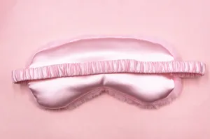 Detail view of pink plush sleep eye mask featuring silky satin finish and elastic band