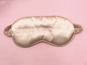 Detailed view of the smooth champagne gold silk sleep mask with an elastic strap