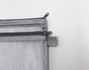 Detalle macro de un portadocumentos de malla gris que muestra la textura y las cremalleras
