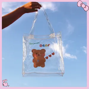 Borsa tote in PVC trasparente con simpatico orso tenuta contro un cielo blu chiaro