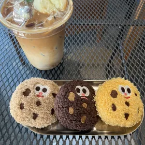 Detailed view of three cute cartoon cookie plush pendants on a tray at a cafe