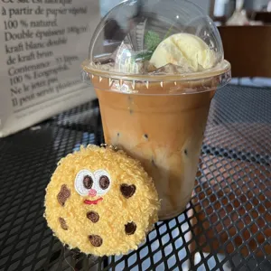 Cute plush cookie cartoon brooch and keychain displayed next to a cup of iced coffee