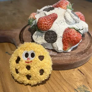 Close-up of cute yellow plush cartoon cookie pin featuring soft curly texture and funny eyes