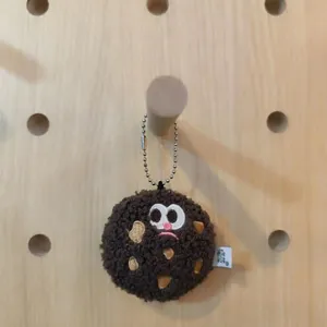 Detail view of cute plush chocolate chip cookie keychain on wooden pegboard