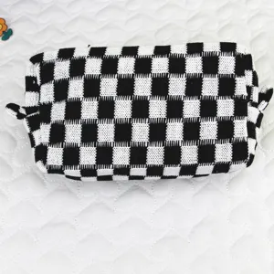 Primer plano de un neceser de punto a cuadros blancos y negros con textura detallada.