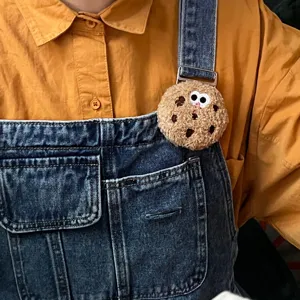 Cute plush cookie brooch with cartoon eyes pinned on denim overalls accessory
