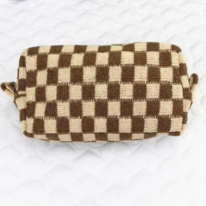 Detalle de neceser de punto a cuadros marrones y beige con textura suave de hilo de lana