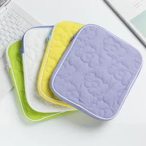 Dettaglio di quattro custodie per iPad trapuntate colorate con motivi floreali su tavolo.