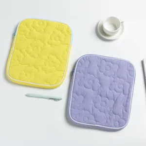 Vista dettagliata delle custodie per iPad trapuntate con motivo floreale giallo e viola.