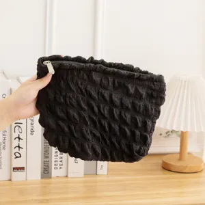 Detalle de un neceser de maquillaje negro con textura de burbuja y cremallera.