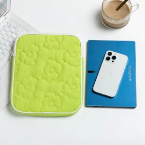 Custodia trapuntata verde lime per tablet con motivi floreali accanto a un iPad