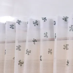 Macro detail of French lace sheer window curtain with delicate embroidered bowknot patterns