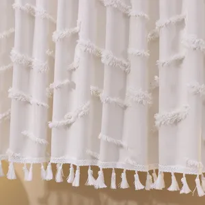 Detailed macro view of white French style lace curtain with tufted texture and fringe tassels