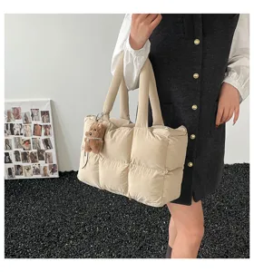 Detail shot of the quilted beige puffer tote bag featuring soft padding and cute bear charm.