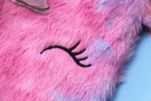 Close-up of soft pink plush unicorn bag with black embroidered eyelash detail