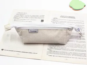 Dettaglio dell'astuccio in velluto a coste crema con texture a rilievo e cerniera