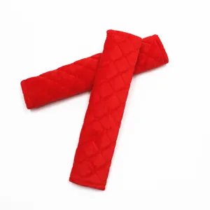 Detailed view of red plush car seat belt shoulder pads with diamond quilted texture