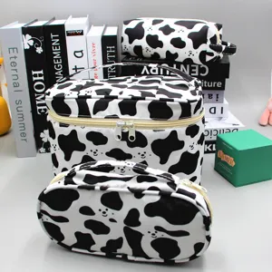 Driedelige cosmetische tas set met koeienprint, inclusief grote tas en een pennenzakje.