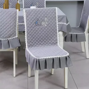 Detail of grey quilted dining chair cover with white lace trim and sailboat embroidery