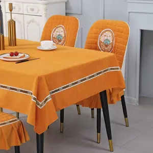 Detailed view of orange corduroy tablecloth and matching curved chair covers with floral embroidery