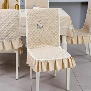 Detail view of beige quilted chair cover set with lace trim and sailboat embroidery