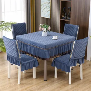 Dettaglio della tovaglia blu trapuntata e coprisedie con gonna abbinati in sala da pranzo.