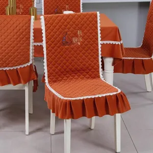 Detail view of orange quilted dining chair cover set with lace trim and embroidery