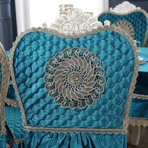 Detail of teal quilted velvet chair cover with gold lace and central embroidery