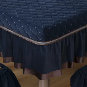 Primo piano di una tovaglia trapuntata blu navy con bordo a balze marrone e nastro di raso.
