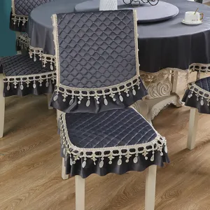 Coprisedie trapuntati grigio scuro e tovaglia rotonda coordinata con pizzi eleganti.