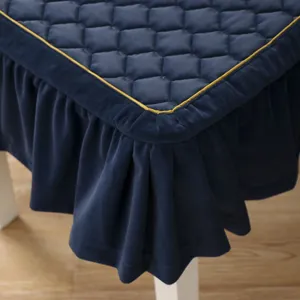 Dettaglio del coprisedia trapuntato blu navy con gonna a balze e bordino dorato.