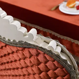 Detailed macro view of luxurious orange velvet quilted chair cover featuring elegant lace trim