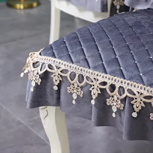 Gros plan d'un élégant coussin de chaise matelassé gris avec bordure en dentelle beige.