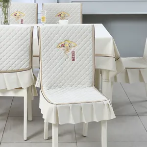 Close-up detail of cream quilted dining chair cover with elegant floral fan embroidery
