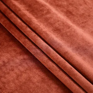 Macro close-up detail of soft rust-orange velvet fabric with a luxurious smooth texture