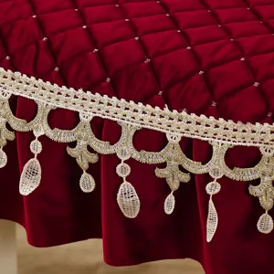 Dettaglio di una tovaglia rotonda in velluto rosso di lusso con pizzo dorato e nappine eleganti