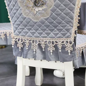Détail d'une housse de chaise matelassée grise avec dentelle et broderie fine.