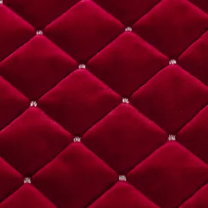 Dettaglio macro del tessuto in velluto rosso vino con motivo a rombi trapuntati e cuciture