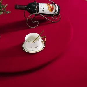 Primo piano della tovaglia rotonda in velluto rosso scuro con elegante tavola apparecchiata.