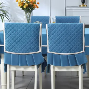Rear view detail of blue quilted dining chair covers with white trim and pleated skirts.