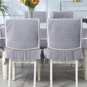 Elegant grey quilted dining chair covers with ruffle detail and matching tablecloth