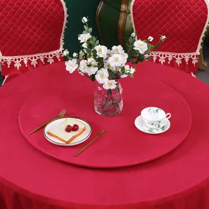Nappe ronde rouge et housses de chaise en dentelle sur una table avec des fleurs